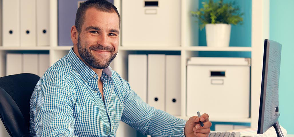 Man smiling sitting at his desk. 